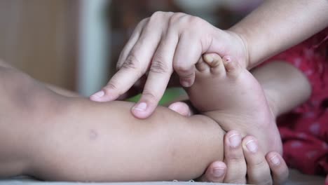 mother caring for baby's leg and feet