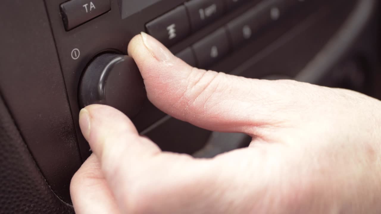 Hand turning dials on a car radio close up shot