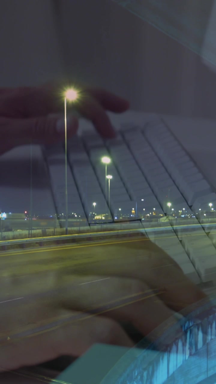 Animation of hands working on laptop over sped up traffic in city at night