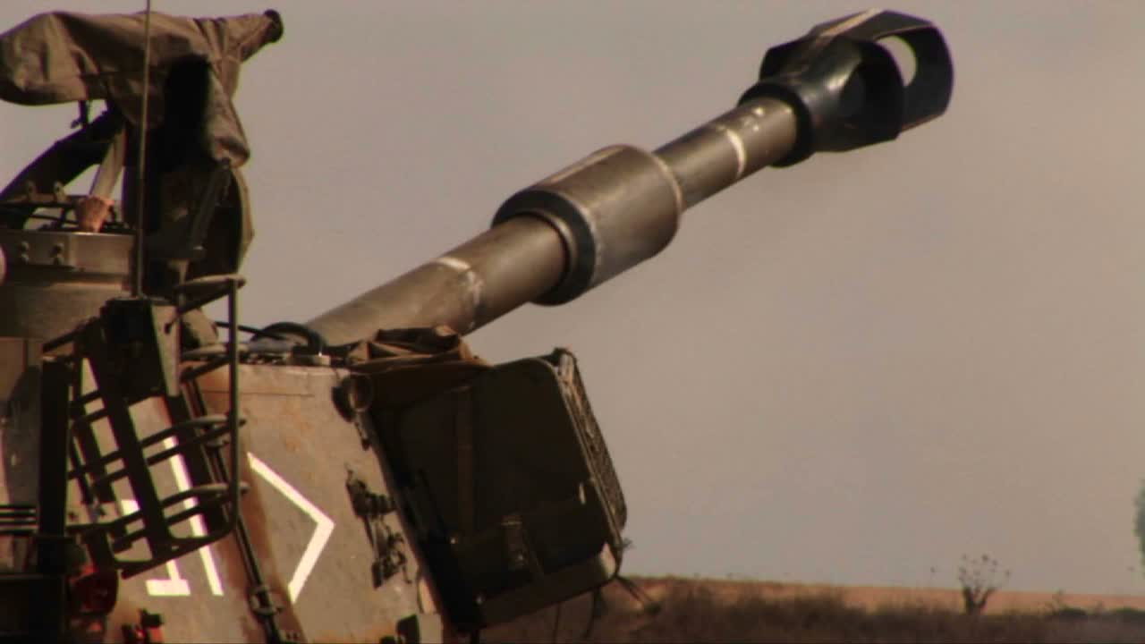 un tanque del ejército dispara y retrocede en un campo de batalla en el medio oriente