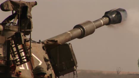 un tanque del ejército dispara y retrocede en un campo de batalla en el medio oriente