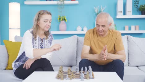 the woman beats her husband in a game of chess. happy couple.