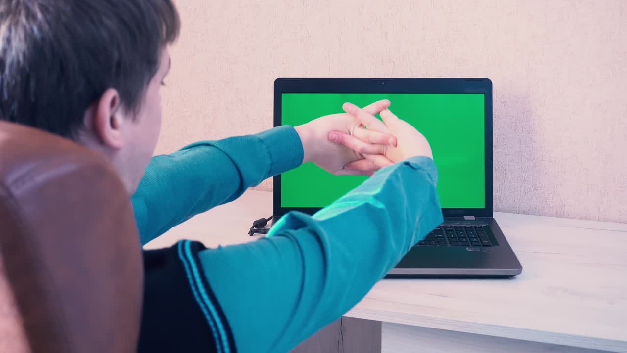 un hombre se pone una máscara protectora antes de comenzar a trabajar en una computadora portátil a través de comunicación de video, tecla de croma en la pantalla de la computadora portatil