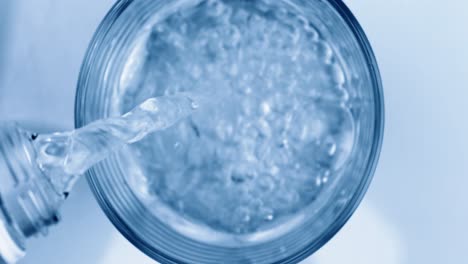 pouring fresh pure sparkling water from bottle into a glass