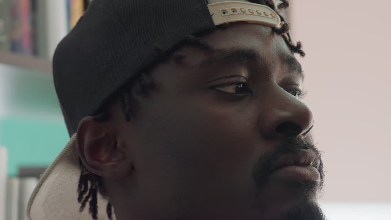 Extreme close up of man wearing cap with intense focused expression while scanning bookshelf for book in library, highlighting curiosity, and dedication to learning in academic setting