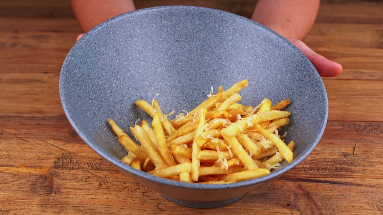 Detailed close up of French fries with grated cheese displayed on its plate
