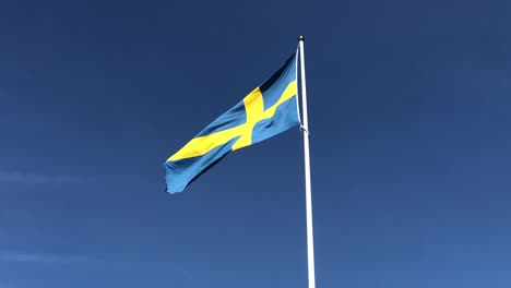 Swedish-flag-in-the-wind-and-tilt-down-to-an-old-swedish-car-with-trailer