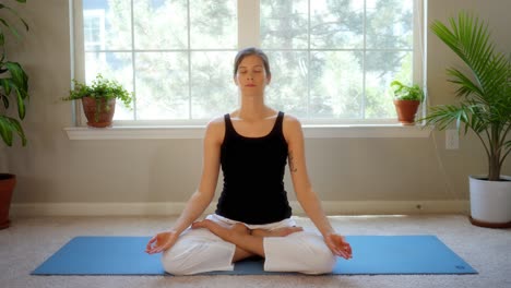 serene young female yoga teacher meditates in a pleasant home studio