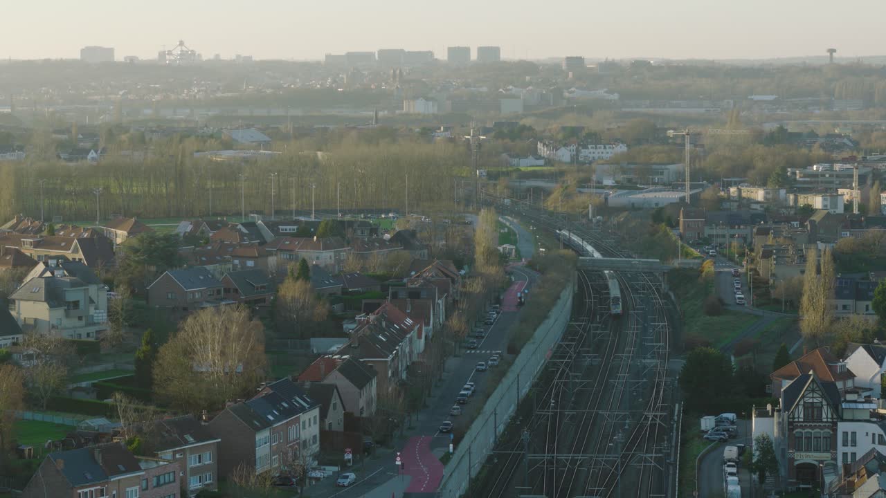 Belgium city and moving train on railway tracks, aerial view