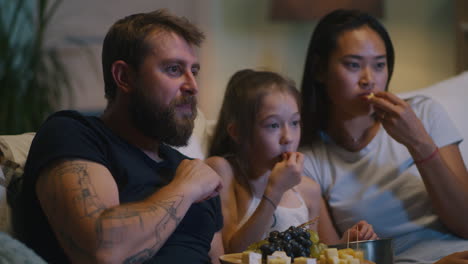 familie beim fernsehen und beim essen von snacks