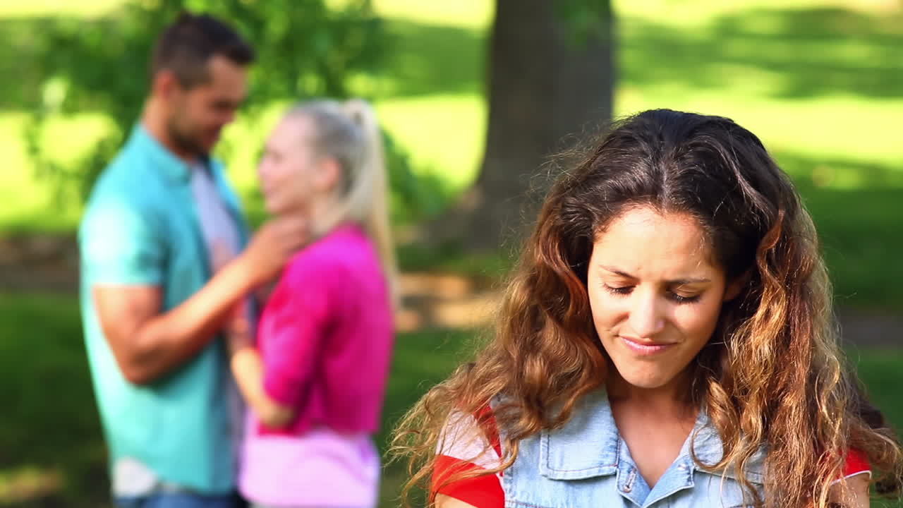 una chica molesta viendo a su enamorado coquetear con otra chica.