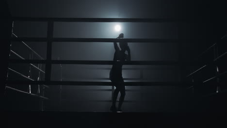 silhouette of a boxer training in a dark ring