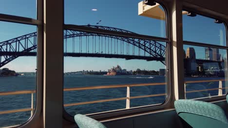 sydney harbour bridge and sydney opera house seen from window of ferry boat - through arch bridge in sydney, nsw, australia