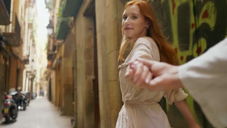 closeup woman holding man hand in old city street. pov of romantic couple hands