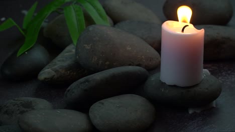 una vela ardiendo sobre rocas con una hoja verde para crear un ambiente espiritual