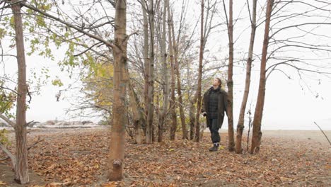 woman walking through tall tree forest on a cold foggy day