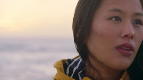 portrait of happy asian woman enjoying peaceful contemplation exploring carefree lifestyle relaxing on beach feeling positive at sunrise