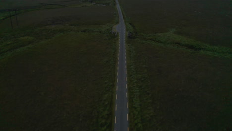 Vista-De-ángulo-Alto-De-La-Estrecha-Carretera-Rural-Con-Líneas-Discontinuas-Amarillas-A-Los-Lados.-Incline-Hacia-Arriba-Para-Revelar-El-Paisaje.-Irlanda