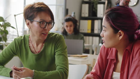 female mentor working with young asian trainee in office