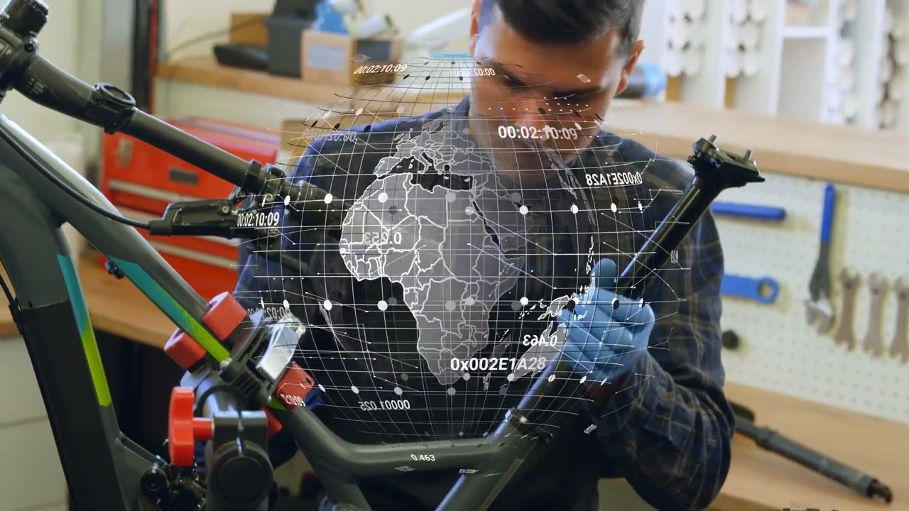 Tecnico riparatore che si china sulla bici individuando un bullone del reggisella allentato, allineando il morsetto, con un globo che si sovrappone al telaio.