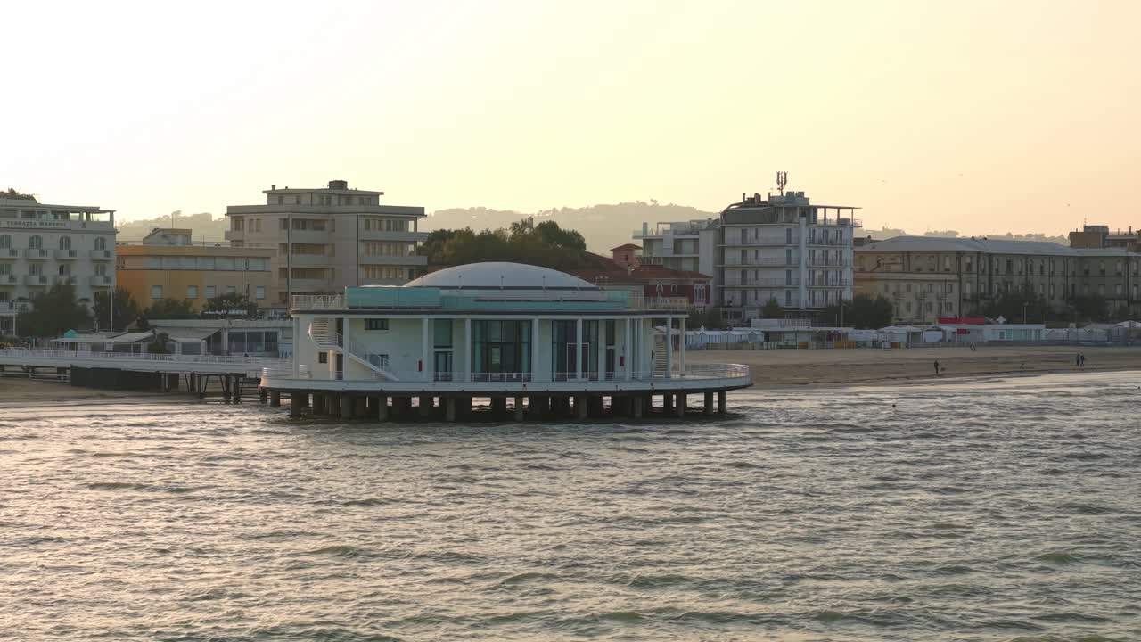 Low aerial orbit of Senigallia, Italy Rotunda of the Sea with sunset beach and city
