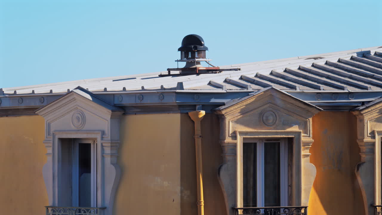 Close up of the facade and rooftop of a yellow building in Nice, France
