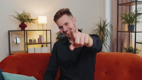 young bearded man smiling, pointing to camera, choosing lucky winner, indicating, inviting, approve