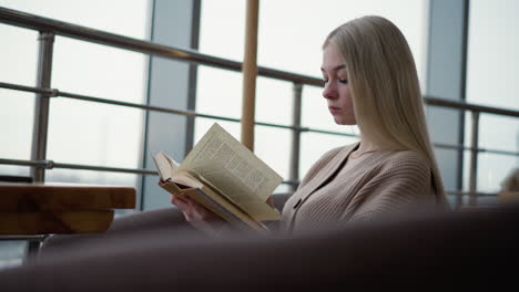 high school student preparing for exam while reading and studying at home, flipping to a new page in book with focused concentration as natural light illuminates workspace