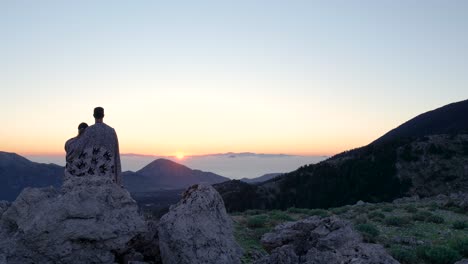 una pareja observando el amanecer desde la cima de la montaña.