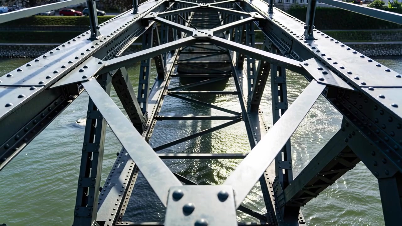 Pulling back after closeup, camera revealing central truss span over river, showing riveted plate