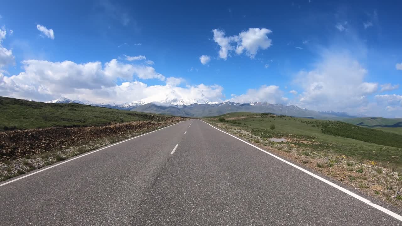 Guida di un'auto su strada (punto di vista). Il Monte Elbrus è visibile sullo sfondo.