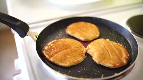 three ruddy golden pancakes in a frying pan, a close-up, white steam.