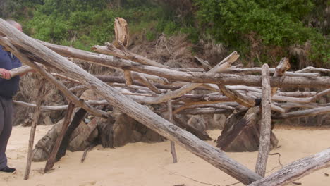 Lone castaway building shelter from driftwood found washed up on the deserted island