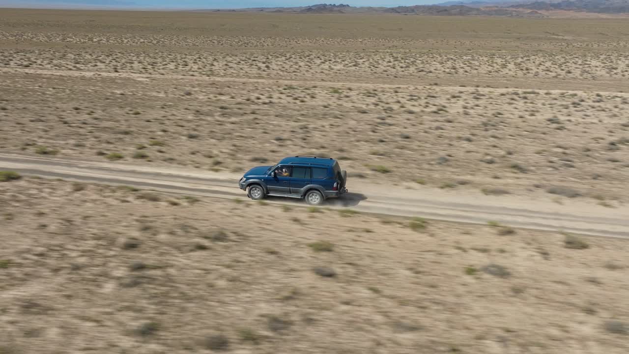 카자흐스탄, 중앙아시아의 차린 캐니언 국립공원 근처의 사막을 가로질러 빠르게 움직이는 차량 - 공중 추적