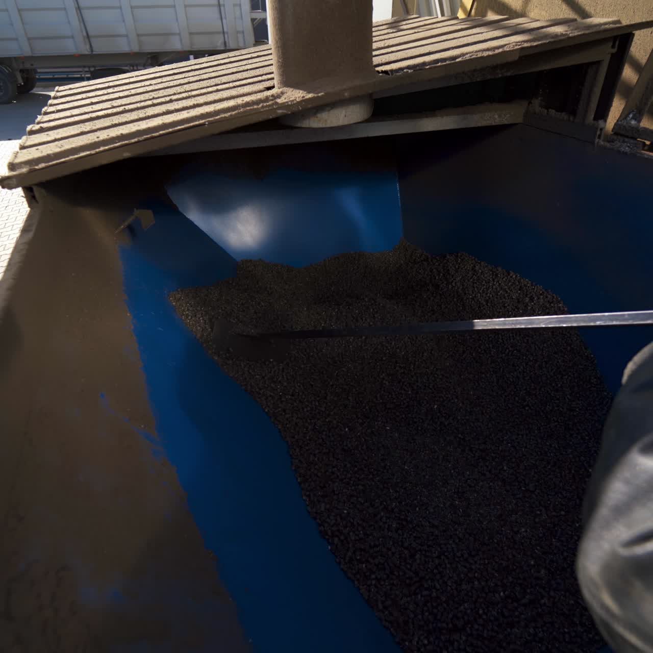 Worker mixes grains in a bin. Industrial equipment for agribusiness. Industry for compound feed. Feed mill. Close-up