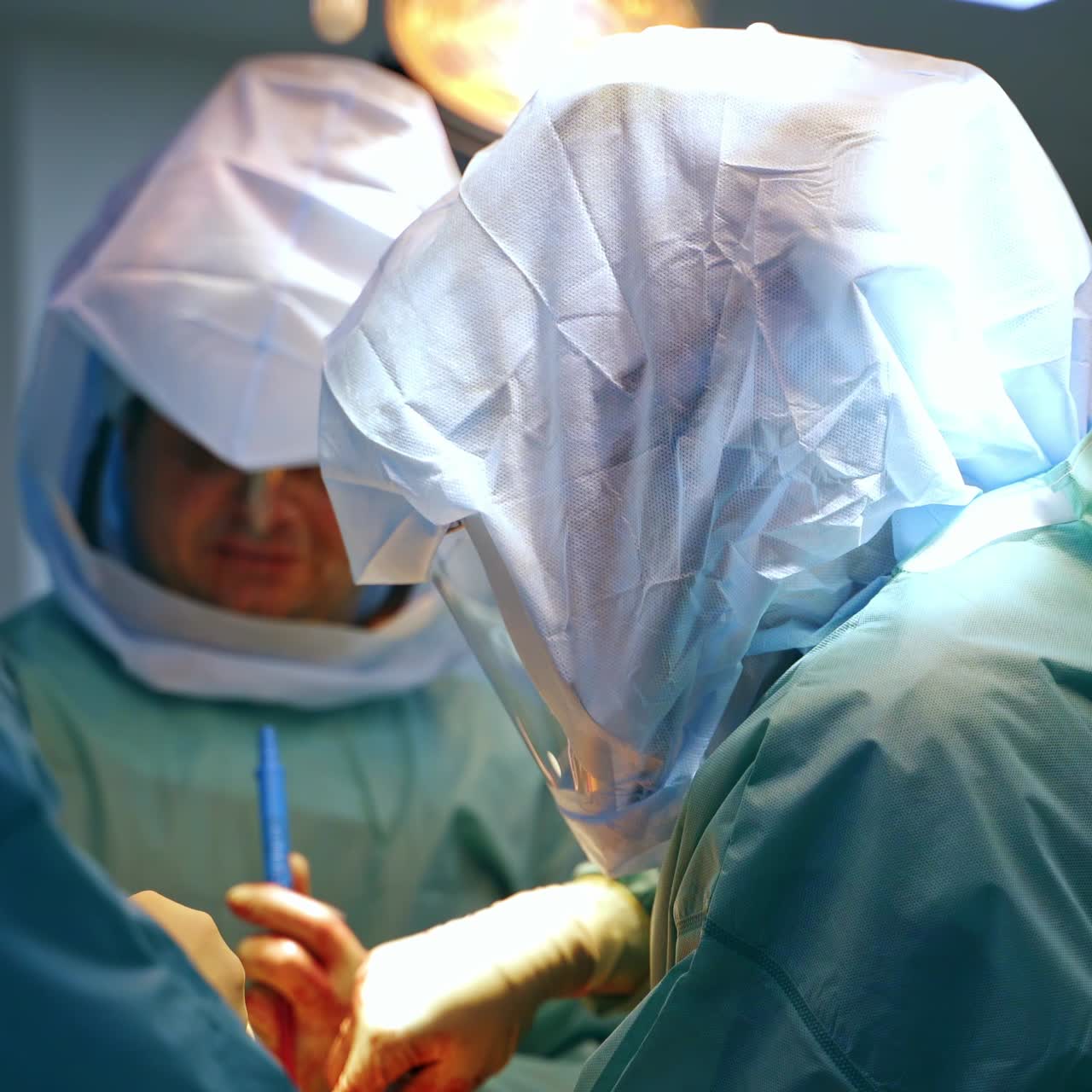Big surgical team working in the operational room. Some professionals wear protective suits at surgery