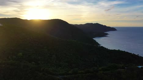 dramatic sunset aerial of st. croix, usvi, showing a golden glow across the sea, trees silhouetted on a remote island point, and the sky painted in brilliant hues of violet, red, and orange