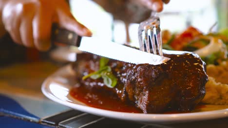 steak cut with knife on plate by asian woman in luxury restaurant. healthy eating and diet concept.