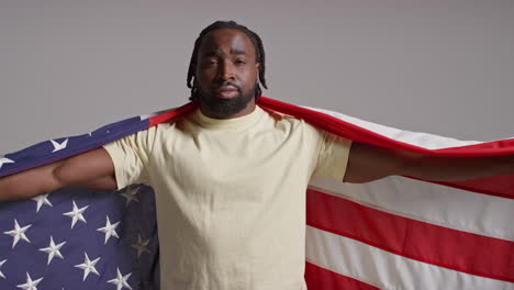 studio portrait shot of man wrapped in american flag celebrating 4th july independence day 5