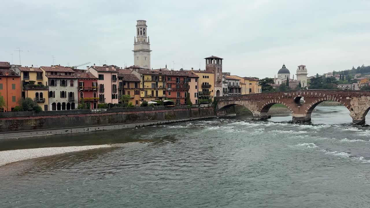 Edifici colorati di Verona lungo il fiume in una giornata nuvolosa. Clip a mano libera.