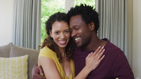 portrait of happy biracial couple looking at camera, embracing and smiling