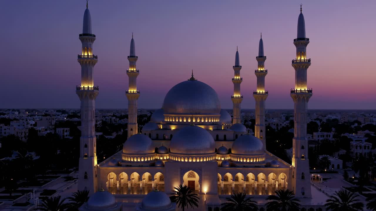 Illuminated mosque stands majestically against the backdrop of a twilight sky, its elegant architecture and glowing lights creating a serene and spiritual atmosphere