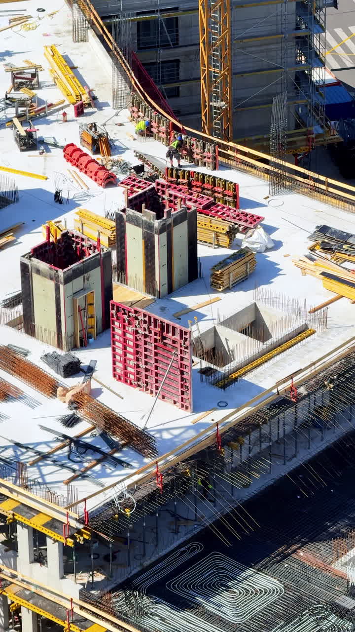 Urban construction activity. Workers are busy on a large construction site with cranes, scaffolding, and building materials during daylight