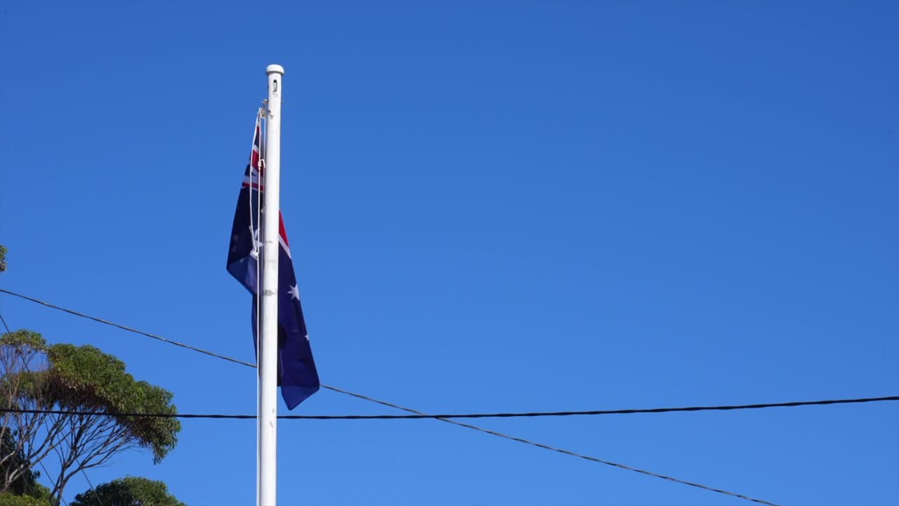 Australsk flag på stang mod klar blå himmel, Tathra, New South Wales, Australien.
