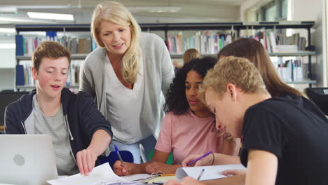 female teacher working with college students in library