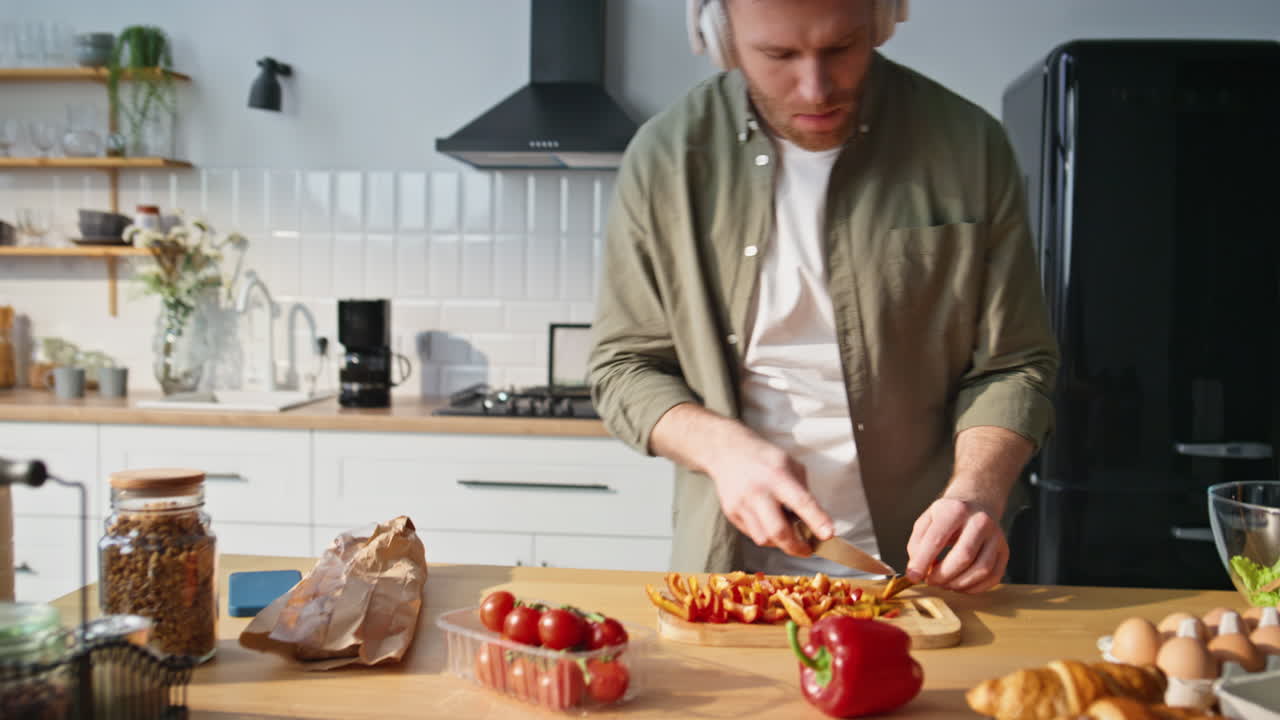 Headphones guy dancing kitchen chopping vegetables closeup. Man preparing salad