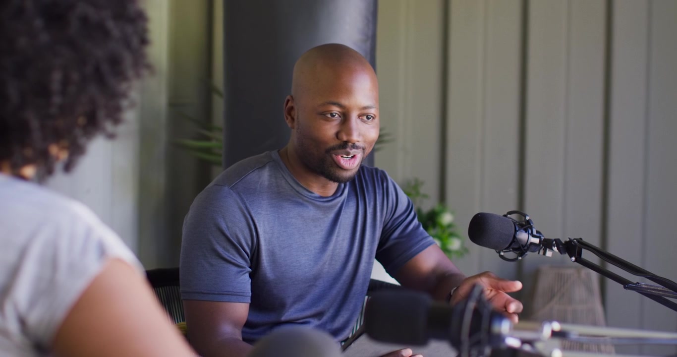Afroamerikanske værter reagerer på stikord, mandlig vært med tablet taler i mikrofoner til studieinterview
