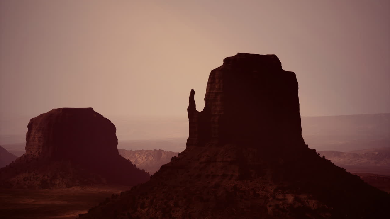 Majestic rock formations rise against a sunset in the desert landscape