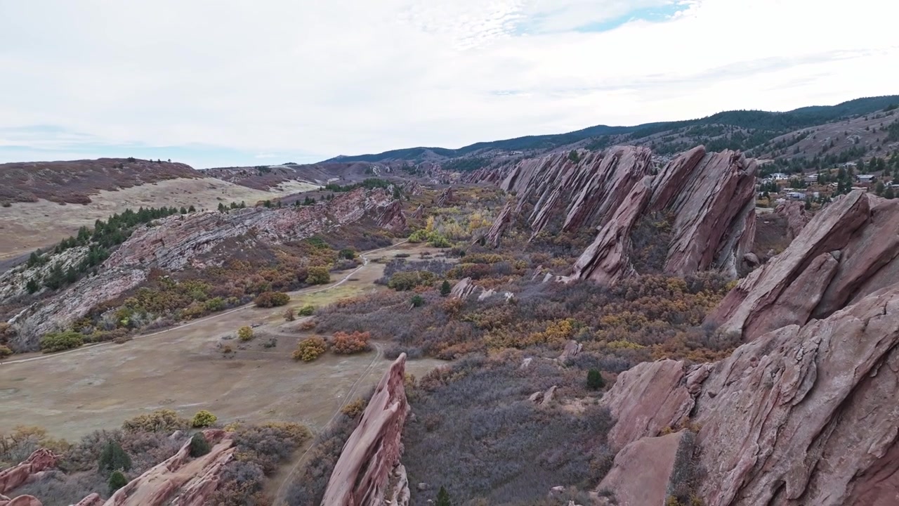 Aerial pullback of a pristine golf course bordered by rugged rocky cliffs and green fairways