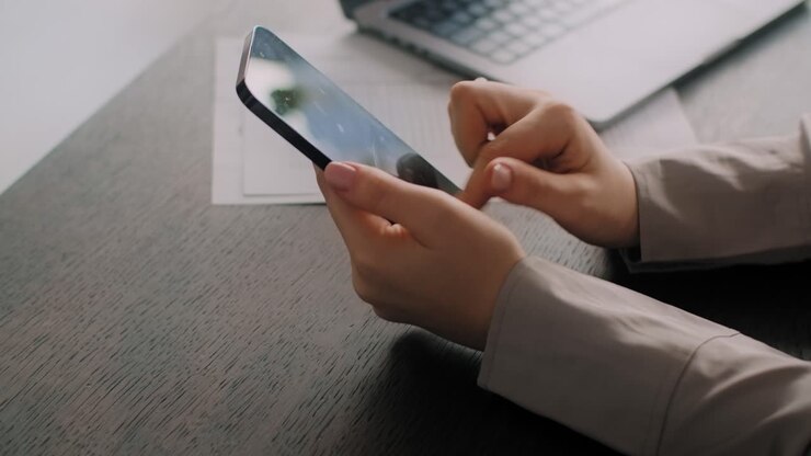 mujer usando un teléfono inteligente en un escritorio